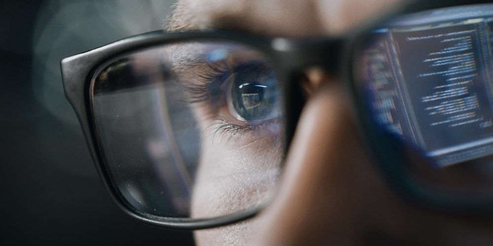 Close-up Portrait of Software Engineer Working on Computer, Line of Code Reflecting in Glasses. Developer Working on Innovative e-Commerce Application using Machine Learning, AI Algorithm, Big Data